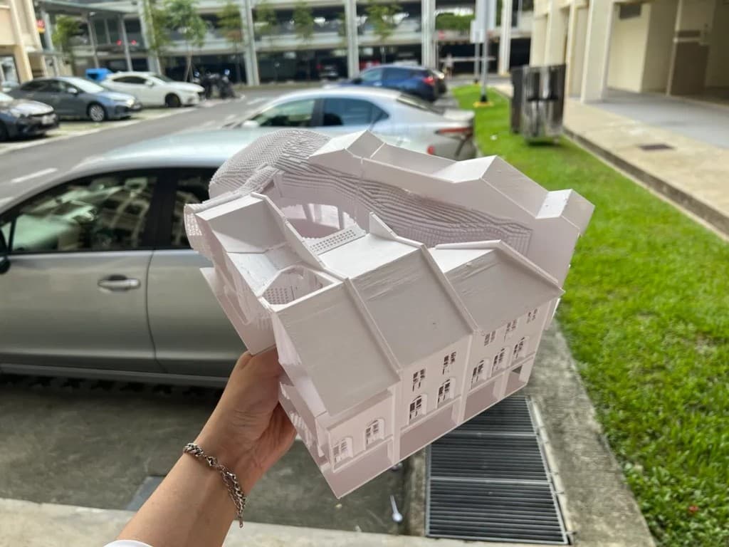 The same shophouse model 3D printed in white PLA, held in a hand